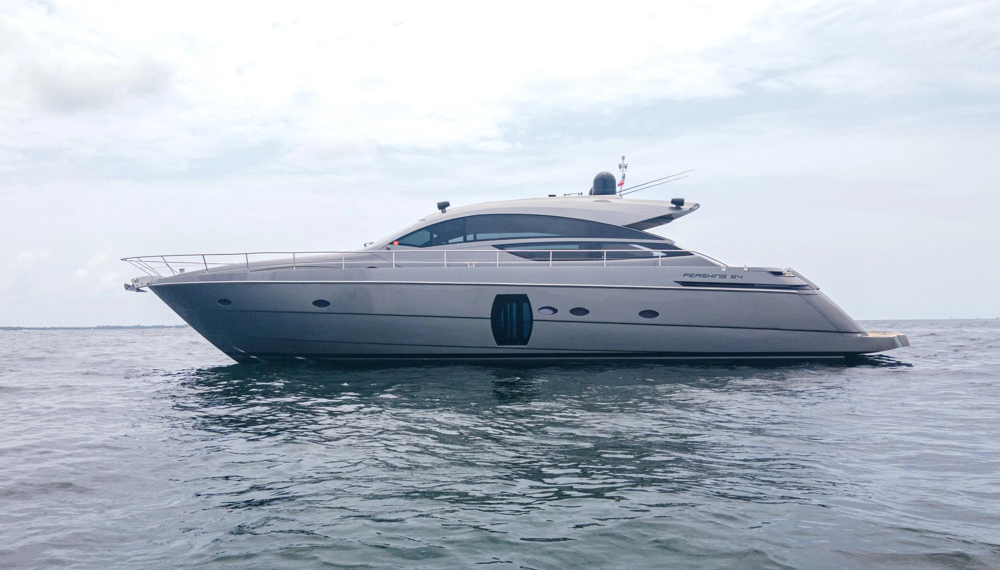2009 Pershing 64 yacht on calm sea under cloudy sky.