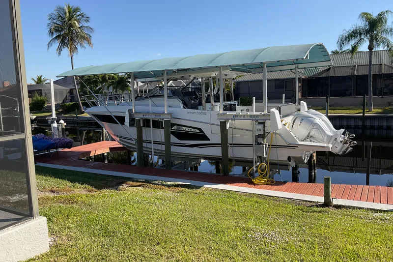  Yacht Photos Pics 2022 Jeanneau Leader 12.5 WA boat docked with canopy, surrounded by palm trees.