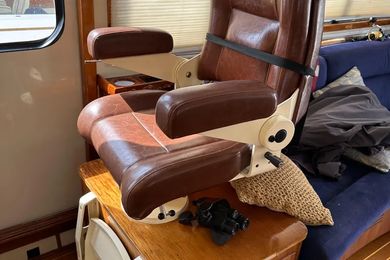 Blue Sora Yacht Photos Pics Brown leather chair inside a 2005 Legacy 42 boat cabin, with a wooden table.