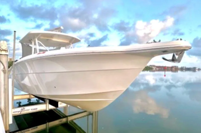  Yacht Photos Pics 2017 Stamas 390 Tarpon boat on lift, reflecting on calm water under cloudy sky.