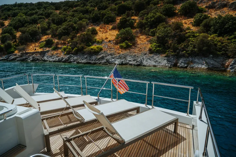  Yacht Photos Pics Luxurious 2014 Azimut 80 yacht deck with sun loungers, American flag, scenic coastal view.