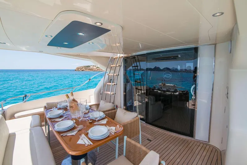  Yacht Photos Pics Luxurious Riva 70 Dolcevita yacht deck with dining setup, overlooking clear blue sea.