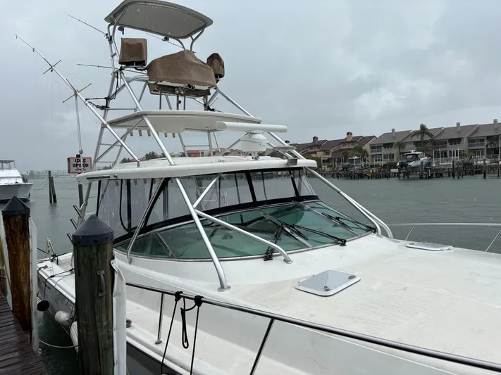  Yacht Photos Pics 2004 Riviera 4000 boat docked on a rainy day, with waterfront homes in the background.