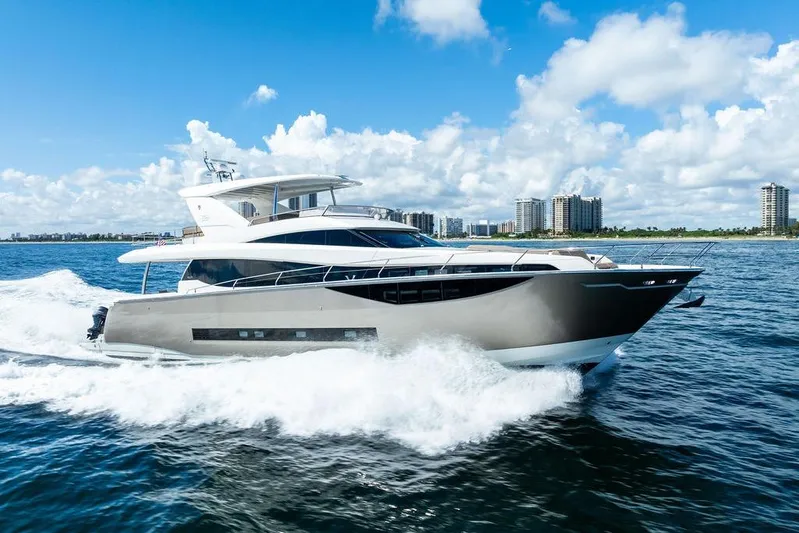 Elevation Yacht Photos Pics Luxury 2016 Prestige 750 yacht cruising on open water, city skyline in background.