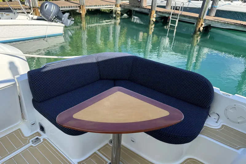 Swell Yacht Photos Pics Cozy seating area on 2020 Back Cove 34O boat with triangular table, docked by clear water.