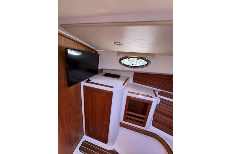 Swell Yacht Photos Pics 2020 Back Cove 34O cabin interior with TV, wood accents, and porthole window.