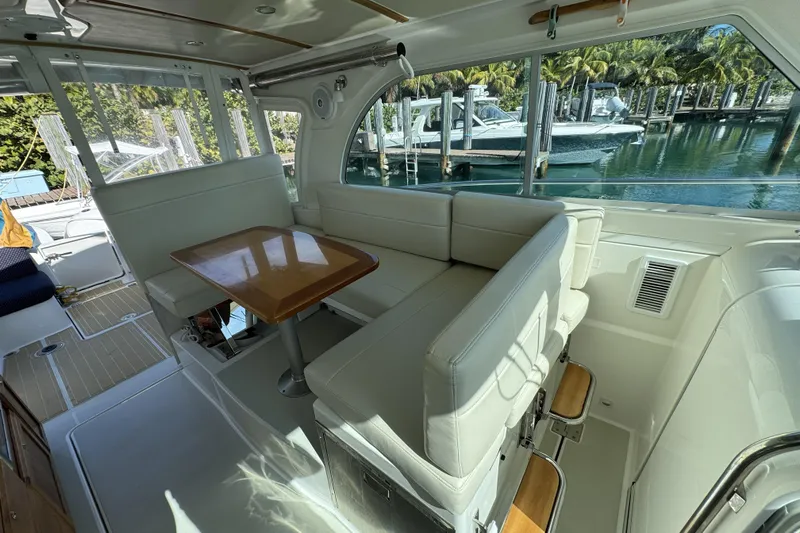 Swell Yacht Photos Pics 2020 Back Cove 34O interior with white seating, wooden table, and marina view.
