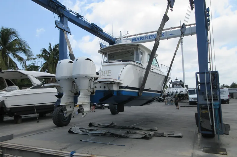 Swell Yacht Photos Pics 2020 Back Cove 34O boat lifted by crane at marina, palm trees in background.