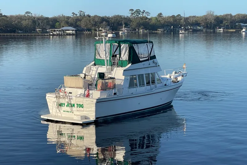 Mary Jean Too Yacht Photos Pics 2003 Mainship 430 Trawler on calm water, featuring green canopy and serene surroundings.