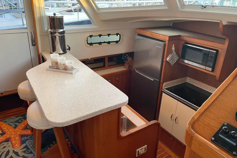 Mary Jean Too Yacht Photos Pics 2003 Mainship 430 Trawler kitchen with bar stools, countertop, fridge, microwave, and stove.