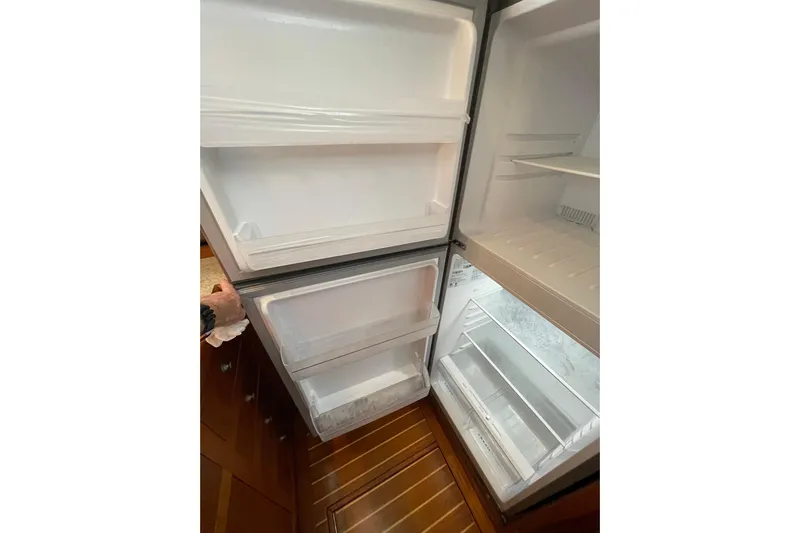 Mary Jean Too Yacht Photos Pics Open refrigerator inside 2003 Mainship 430 Trawler, showcasing spacious interior and wooden flooring.