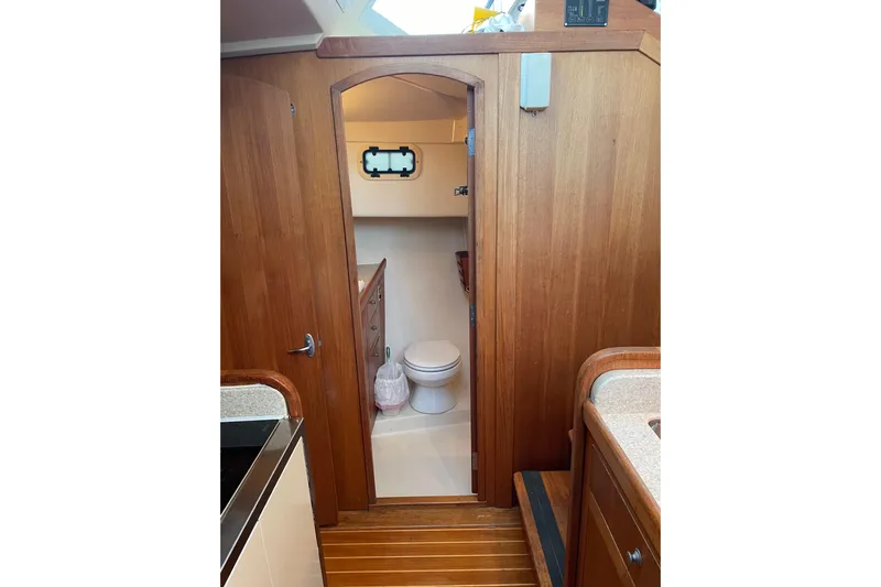 Mary Jean Too Yacht Photos Pics Interior of 2003 Mainship 430 Trawler, featuring a wooden bathroom door and compact toilet.