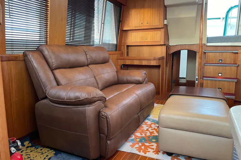 Mary Jean Too Yacht Photos Pics 2003 Mainship 430 Trawler interior with leather sofa, ottoman, and wooden cabinetry.