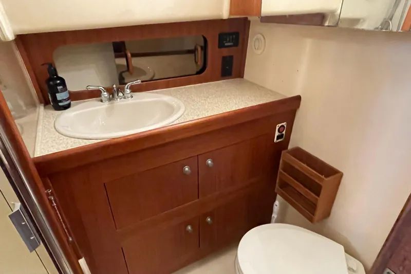 Mary Jean Too Yacht Photos Pics 2003 Mainship 430 Trawler bathroom with sink, mirror, and wooden cabinetry.