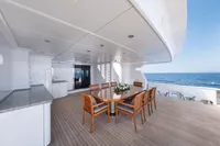 Luxurious yacht deck with dining table, wooden chairs, and ocean view, R.B Dereli 2004 model.