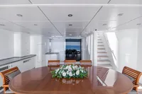Luxurious yacht interior with elegant dining area, wooden table, floral centerpiece, and ocean view.
