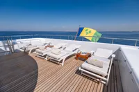Luxurious yacht deck with sun loungers, wooden flooring, and a flag, R.B Dereli 2004 model.
