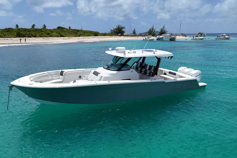  Yacht Photos Pics 2022 Bertram 39 CC boat anchored in clear turquoise water near a sandy beach.