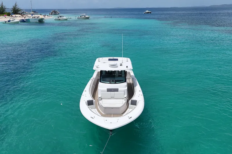  Yacht Photos Pics 2022 Bertram 39 CC boat anchored in clear turquoise waters near a sandy beach.