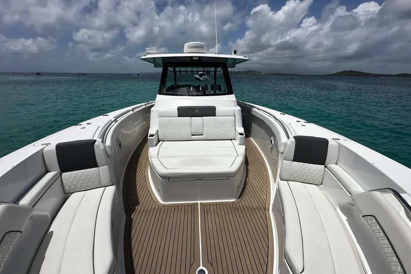  Yacht Photos Pics 2022 Bertram 39 CC boat with spacious seating, on clear turquoise water under cloudy sky.