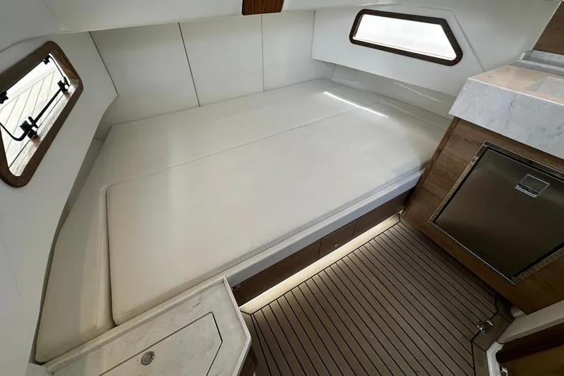  Yacht Photos Pics 2022 Bertram 39 CC cabin interior with bed, windows, and wooden flooring.
