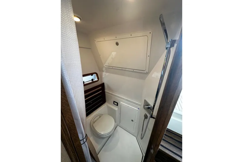  Yacht Photos Pics 2022 Bertram 39 CC boat bathroom with toilet, shower, and storage compartment.