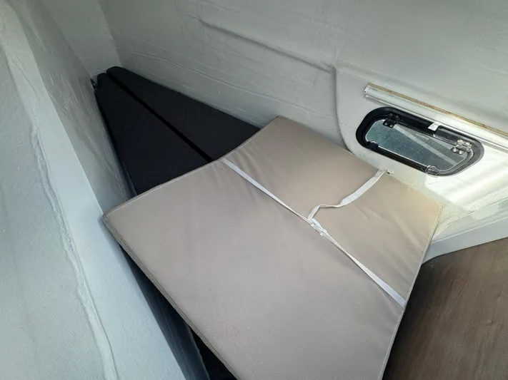  Yacht Photos Pics Interior view of 2023 Bali 4.2 boat cabin with folded mattress and window.