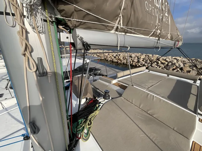  Yacht Photos Pics 2023 Bali 4.2 sailboat deck with ropes and seating, docked by rocky shoreline.