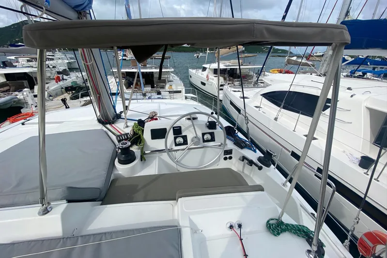 Mirabella Yacht Photos Pics 2022 Bali 4.2 yacht cockpit with steering wheel, docked among other boats.