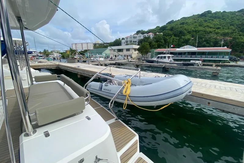 Mirabella Yacht Photos Pics 2022 Bali 4.2 yacht docked with inflatable boat, scenic marina background.