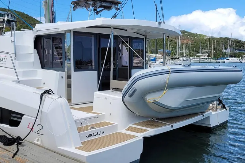 Mirabella Yacht Photos Pics 2022 Bali 4.2 catamaran docked with inflatable boat, scenic marina background.