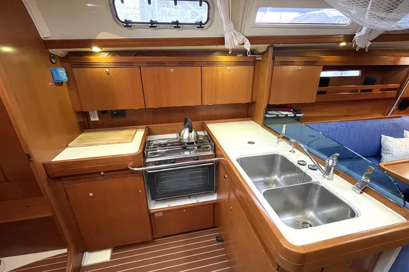 New Journey Yacht Photos Pics 2005 Dufour 40 Performance yacht kitchen with stove, sink, and wooden cabinetry.