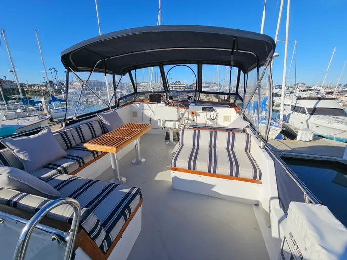 Kolea Yacht Photos Pics 1983 Ocean Alexander 43 yacht with striped seating and canopy in a marina.