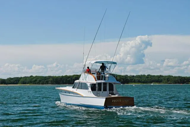 Proud Lady Yacht Photos Pics 1957 Rybovich Convertible boat cruising on a sunny day with two people onboard.