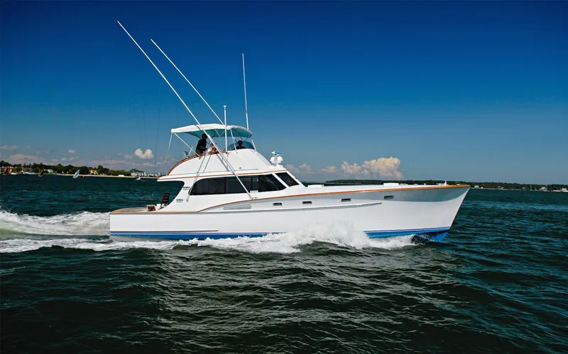 Proud Lady Yacht Photos Pics 1957 Rybovich Convertible yacht cruising on open water under a clear blue sky.