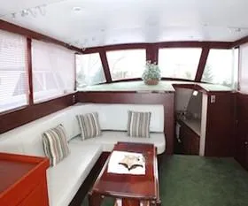 Proud Lady Yacht Photos Pics 1957 Rybovich Convertible yacht interior with white seating, wooden accents, and a small table.