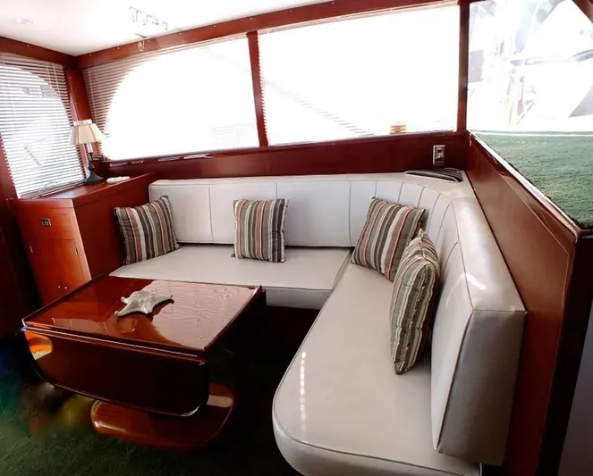 Proud Lady Yacht Photos Pics 1957 Rybovich Convertible yacht interior with white leather seating and striped cushions.