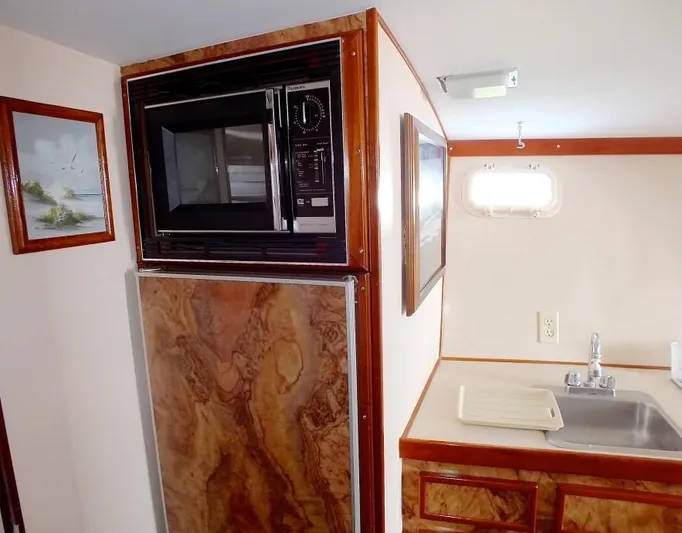 Proud Lady Yacht Photos Pics 1957 Rybovich Convertible yacht kitchen with microwave, sink, and wood paneling.