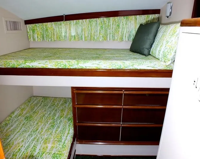 Proud Lady Yacht Photos Pics 1957 Rybovich Convertible interior with green-patterned bunk beds and wooden storage.