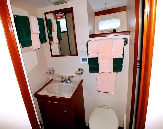 Proud Lady Yacht Photos Pics 1957 Rybovich Convertible yacht bathroom with sink, mirror, and neatly arranged towels.