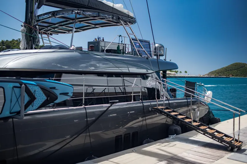 Gracious Yacht Photos Pics Luxurious 2021 Sunreef 60 yacht docked, featuring sleek design and paddleboard on deck.
