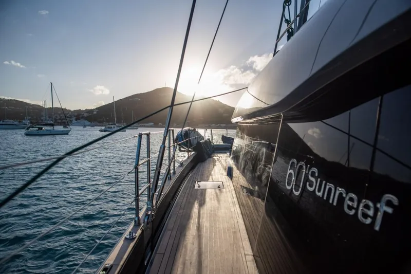 Gracious Yacht Photos Pics Luxurious 2021 Sunreef 60 yacht sailing at sunset with scenic mountain backdrop.
