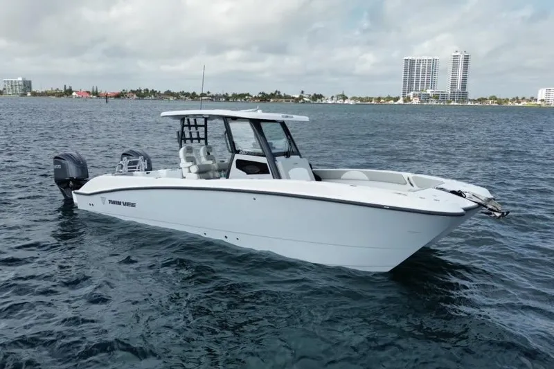  Yacht Photos Pics 2026 Twin Vee 280 GFX2 CC boat on calm water, cityscape in background.