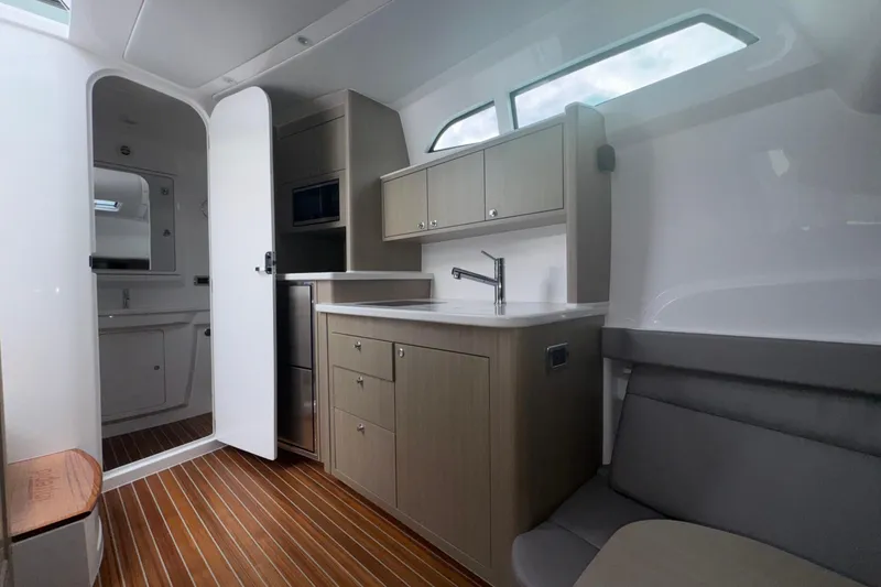  Yacht Photos Pics Modern interior of 2025 Intrepid 51 Panacea yacht with kitchenette and seating area.