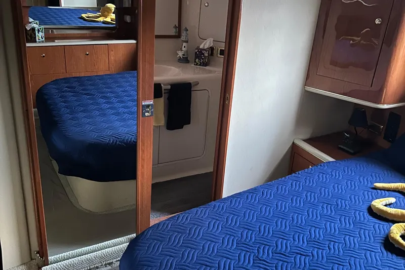 Fathom This Yacht Photos Pics Interior of 2001 Sea Ray 420 Aft Cabin with blue bedding and wooden cabinetry.