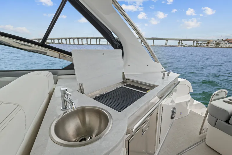 Sojourner Yacht Photos Pics 2024 Regal 33 XO boat with outdoor sink and grill, overlooking a scenic waterway.
