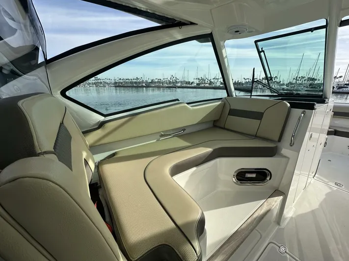 Always Grateful 2 Yacht Photos Pics 2021 Pursuit DC 326 Dual Console interior with beige seating, overlooking marina.