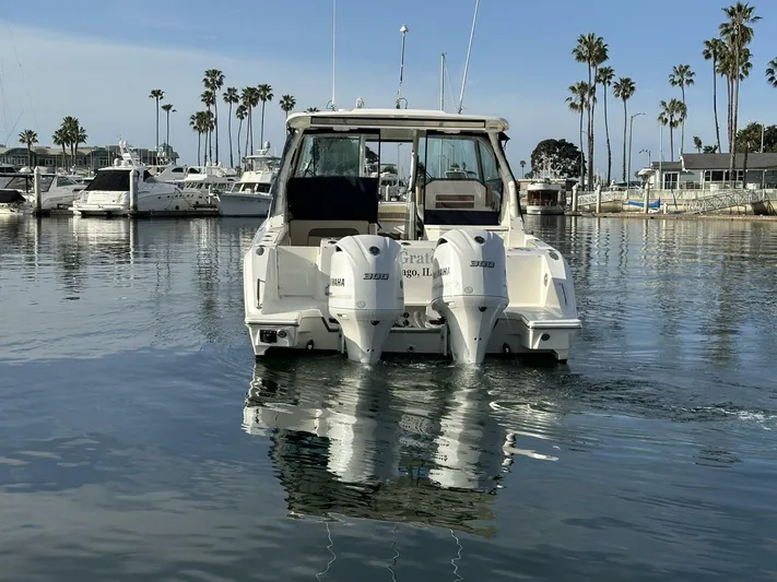 Always Grateful 2 Yacht Photos Pics 2021 Pursuit DC 326 Dual Console boat docked in a marina with palm trees.