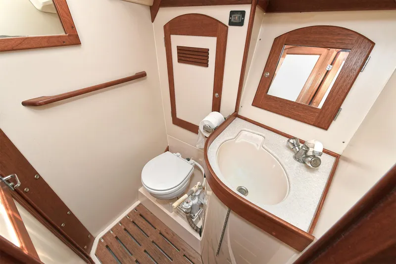 The Verdict III Yacht Photos Pics Compact boat bathroom with wooden accents, featuring a toilet and sink. Sabre 452, 2002 model.