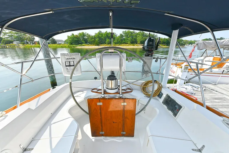 The Verdict III Yacht Photos Pics 2002 Sabre 452 sailboat cockpit with steering wheel, docked by calm waters.